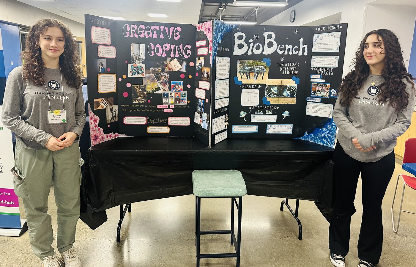 Two Orblynx students standing with their Creative Coping and BioBench project boards at a showcase