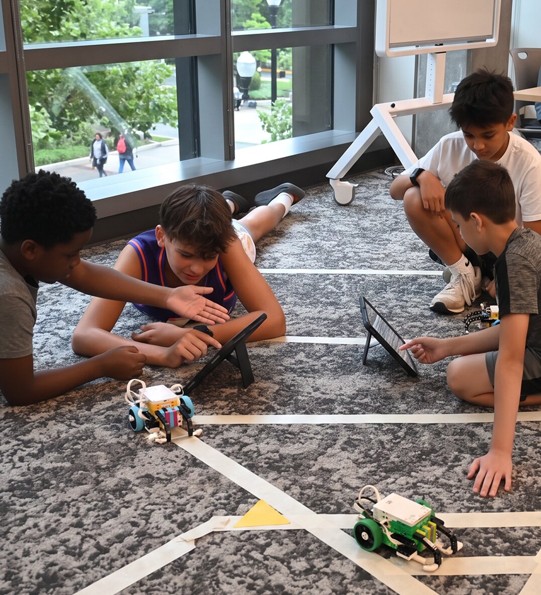 Students programming robots with tablets during a STEM Innovation Lab session